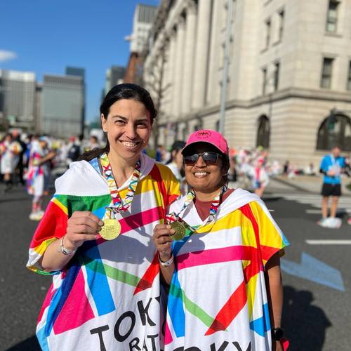 Two runners wearing colorful finisher ponchos and medals
