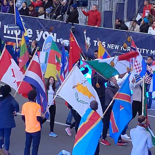 Runners carrying flags of many countries at an international race parade