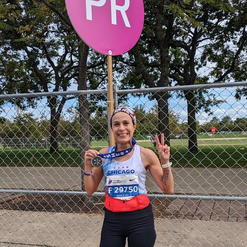 A runner holding a PR sign after a race