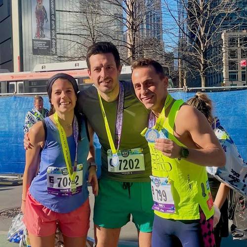 Three runners showing off their finisher medals