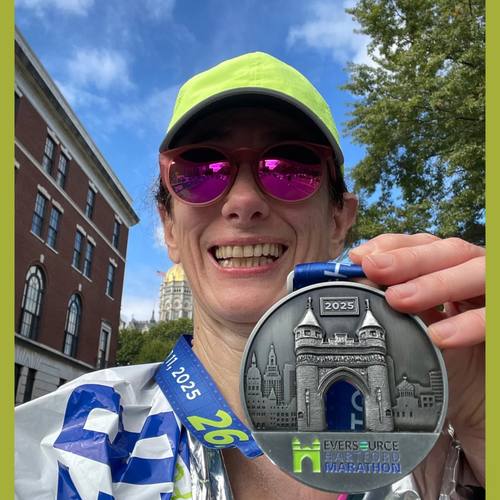 A club member with her Hartford Marathon finisher medal