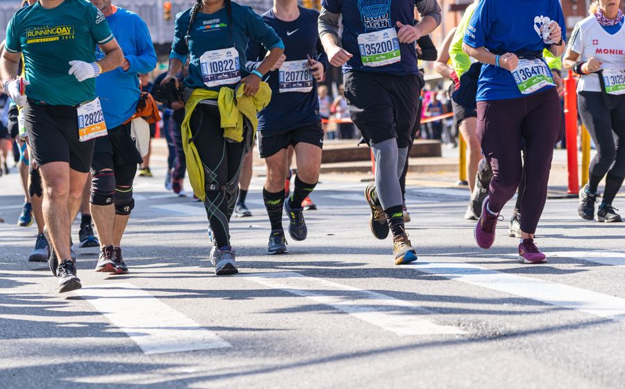 Runners with race bibs on a city street during a marathon